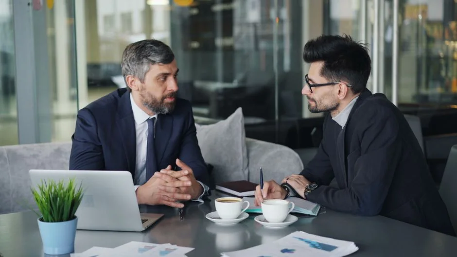 Business professionals discussing data at a desk with a laptop.